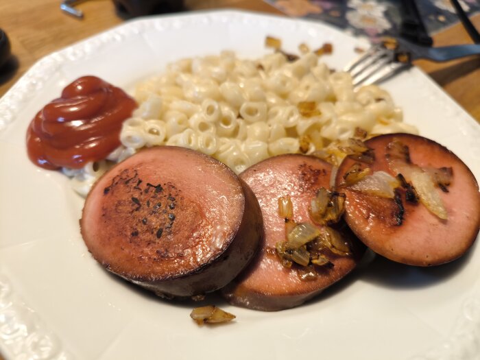 Stekt Jokkmokkskorv med stuvade makaroner och lök på en tallrik, med en klick ketchup på sidan.