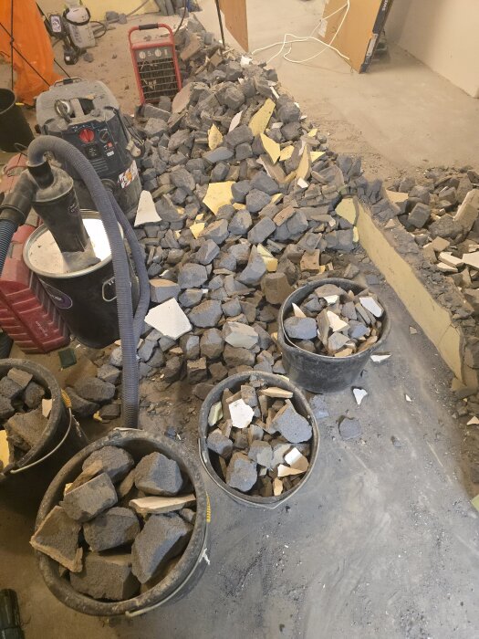 Hinkar fyllda med bitar av lättbetong och murbruk samt en hög med byggavfall i ett renoveringsprojekt.
