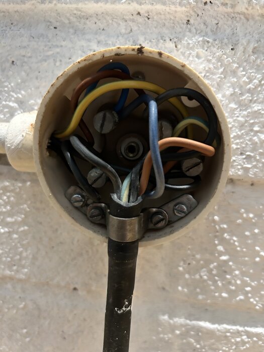 Elektrisk kopplingsdosa med flera kablar och skruvanslutningar i en väggdom, används för installation av spis.