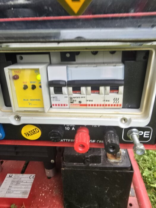 Frontpanelen på ett elverk med anslutningar och instrumentering. Tryckknappar och indikatorlampor syns ihop med brytare och klämmor.