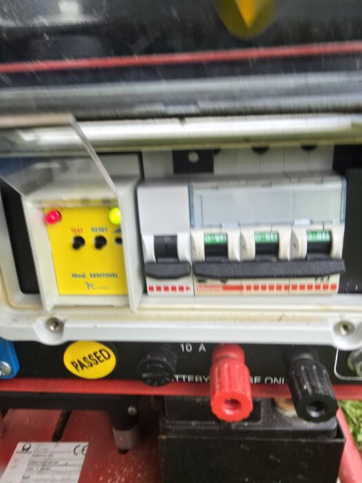 Bild av en kontrollpanel för ett reservkraftsaggregat med flera brytare, ljuspanel och anslutningar. Märkt med en gul "PASSED"-etikett.