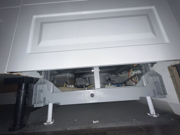 Under diskbänken utan frontpanel visar rör, kablar och apparatfästen.