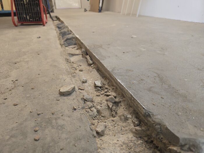 Betonggolv med frilagd ränna och betongrester efter bilning i källaren.