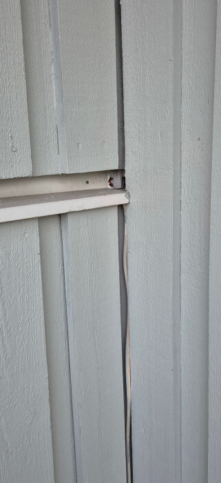 Sprucken plast i hörn av huspanel; skyddsbar av utskjutande tak.