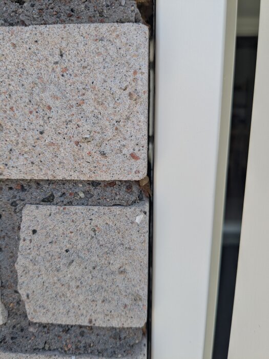 Spricka mellan nyinstallerad altandörr och tegelfasad, visar luckor i dörrkarmens passform mot ytterväggen.