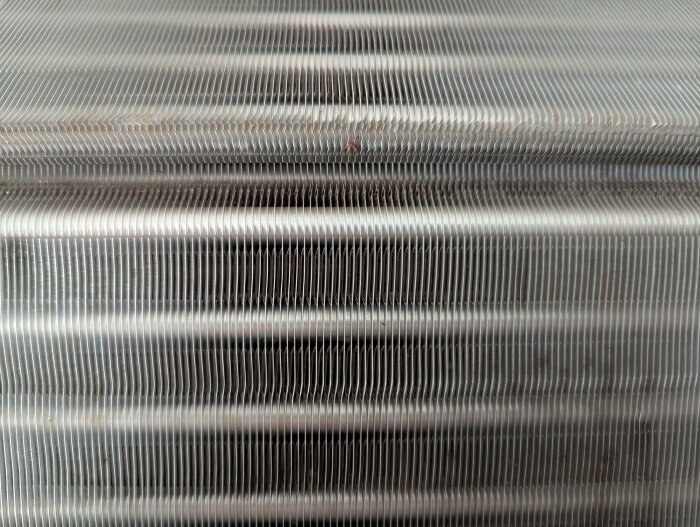 Ren luftvärmepumpstrumma efter rengöring, med synliga metallribbor i närbild. Nästan helt ren efter användning av Julas rengöringsprodukt.