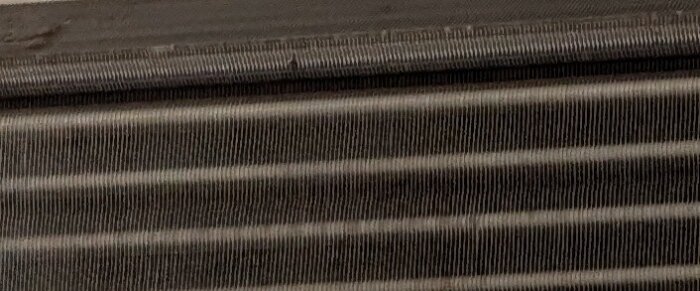 Närbild av en renad luftvärmepumpens komponent efter rengöring med Julas värmepumpsrengöring och pensel.