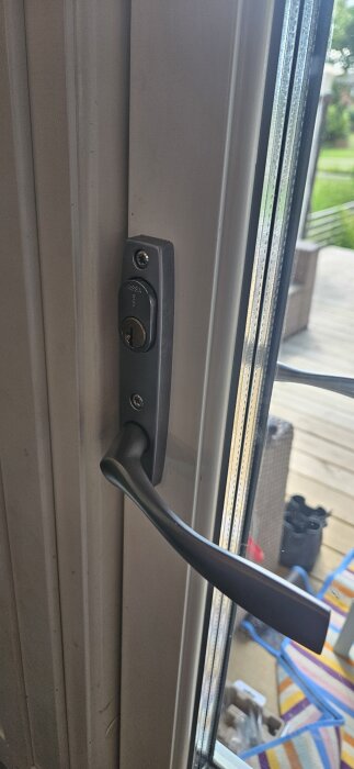 Bild av altandörr med monterat dörrhandtag och Assa-låshus som öppnas genom att tryckas neråt, omgiven av fönster och balkongbakgrund.