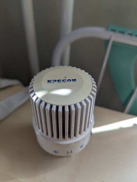 EPECON FLUIDE termostat med ratt och skala för temperaturkontroll, del av fjärrvärmesystem kopplat till radiator.