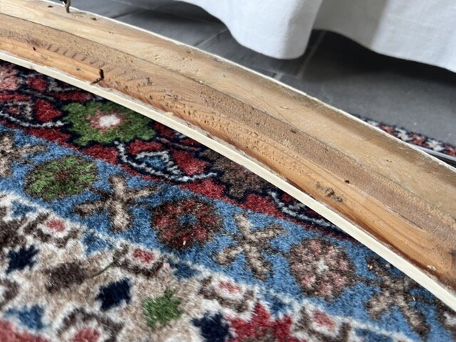 Fasettslipat glas i träbehållare, syns på en färgglad matta, med del av äldre träram som håller glaset.