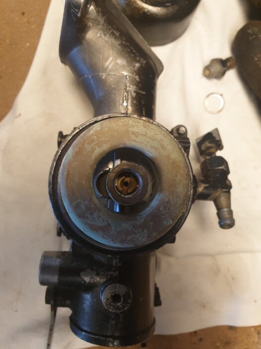 Förgasare till Briggs-motor 10 hp, med fokus på flottör och möjliga fel relaterade till bränsleläckage och motoroljekontamination.