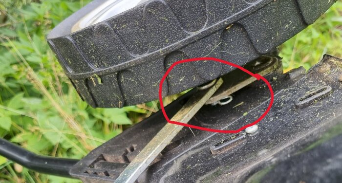 Hjul på en Falke elgräsklippare med en röd ring runt bult och sprint som behöver sättas tillbaka.