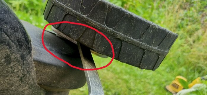 Närbild på ett hjul på en Falke elgräsklippare som visar en bult och sprint, delvis täckta och markerade med en röd cirkel.