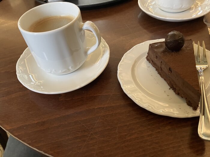En kopp kaffe och en bit chokladkaka på ett träbord.