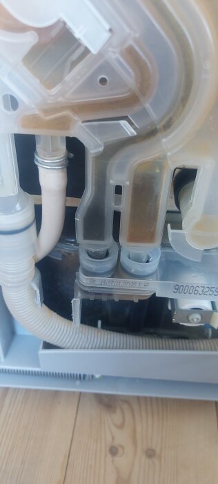 Diskmaskinens undersida med plaströr och kopplingar, synligt läckage från en "pipa" i en Bosch Silence-modell. Problem med fastsättning.
