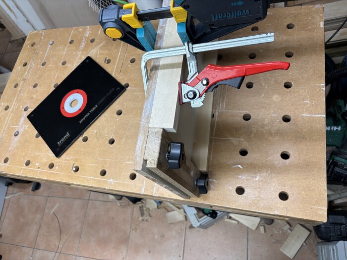 Handhållen maskin monterad på arbetsbänk med en platta, en del av ett träprojekt i en verkstad.