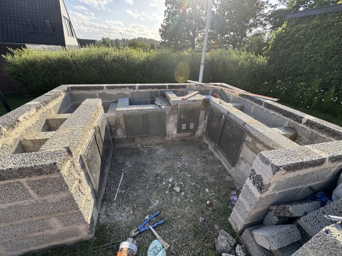 Murad utomhusstruktur nästan färdig, med synliga verktyg och material. Byggprojekt under arbete i trädgårdsmiljö.