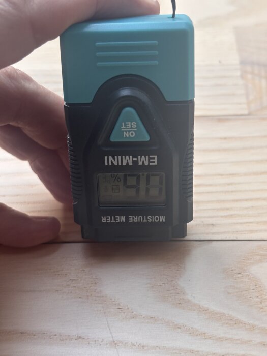 Fuktmätare visar 9,0 % på träbräda inomhus.