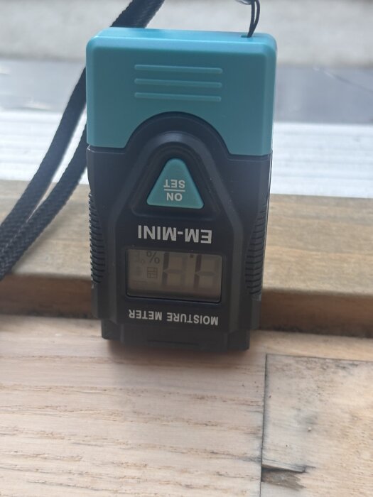 Fuktmätare på träytan vid altandörr, visar förhöjd fukthalt.