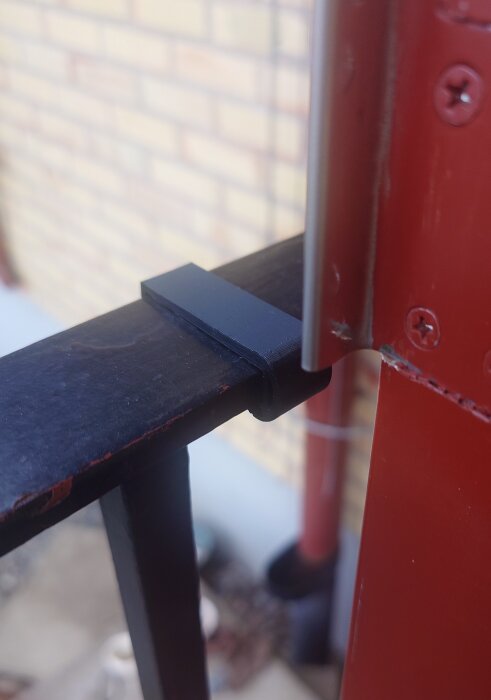 Skydd mellan svart räcke och röd dörr, del av unikt designprojekt.