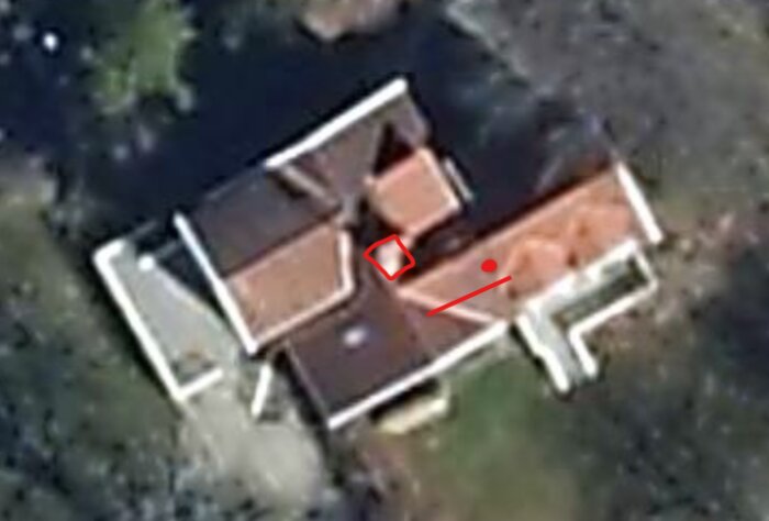Luftfoto av ett hus med markerad röd prick och fyrkant på taket. Huset har flera taksektioner och en takkupa.