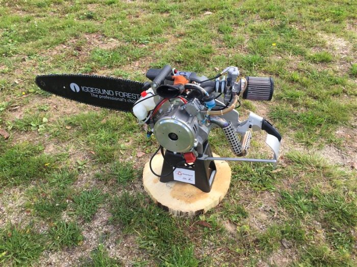 Motorsåg med Wankelmotor placerad på en stubbe, omgiven av gräs. Utformad för höga varvtal, upp till 17 000 rpm.