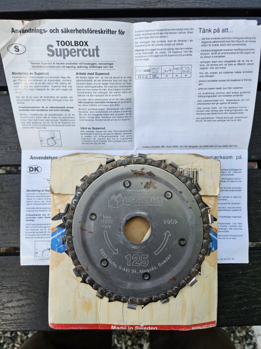 Cirkelsågklinga från Toolbox Supercut med monteringsinstruktioner i bakgrunden. Klingan har patentnummer och specifikationer synliga.