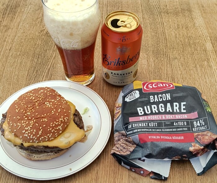 Hamburgare med ost på tallrik, Scan baconburgare-förpackning och Eriksberg Karaktär öl på ett bord.