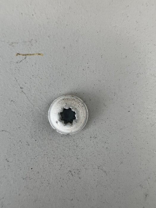 Bild på en skruv med 8-spårsmönster, inte passande för Torx T10, monterad på en slät yta. Användare söker identifiering av skruvtypen.