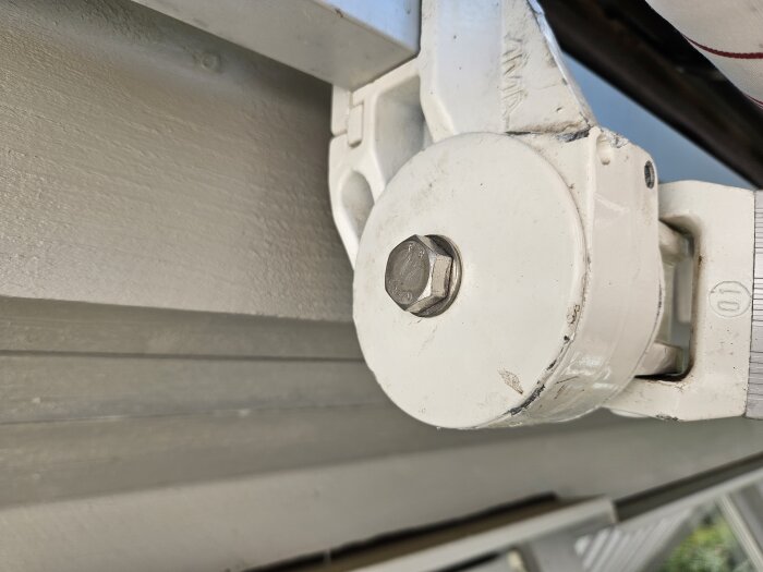 Närbild av vit metallbeslag och skruv på byggkonstruktion, del av justerat område som nämns ha sjunkit.