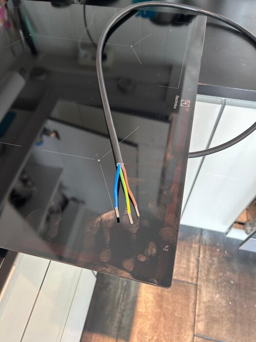 Electrolux induktionshäll med anslutningskabel visar fyra synliga kablar; svart (L1) saknas, vilket orsakar funderingar kring en- och tvåfasanslutning.