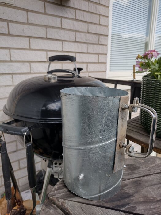 Egenbyggd koltändare av metall på ett bord vid en klotgrill.