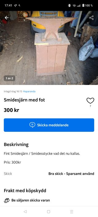 Smidesjärn placerat på en träblock i ett garage, med ved i bakgrunden och en gul gräsklippare synlig.