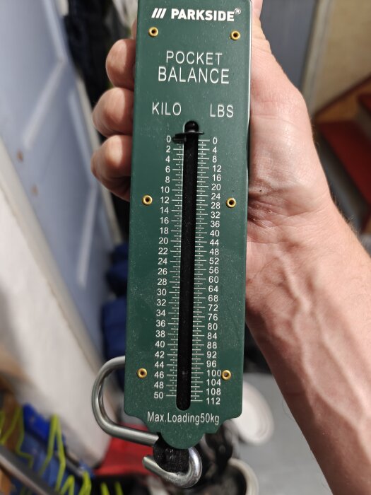 Man håller en grön Parkside fickvåg märkt "Pocket Balance" med en maxlast på 50 kg.