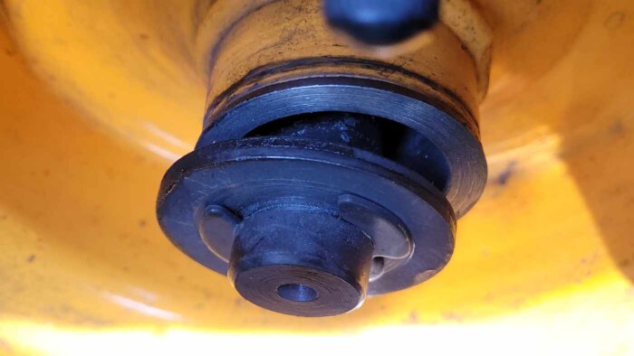 Närbild av ett ostabilt gräsklipparhjul på en trädgårdstraktor, där hjulet kan röra sig fram och tillbaka på axeln.