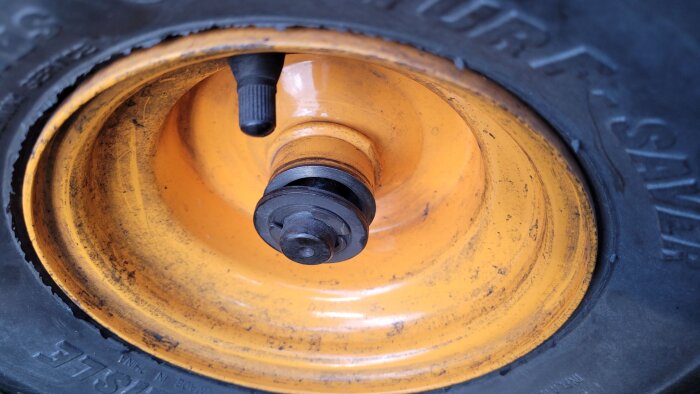 Gult hjul på en trädgårdstraktor med osäker montering; centrumdel och axel synliga.