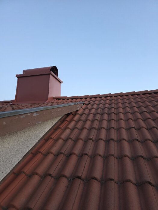 Tegeltak med röd skorsten och vindskiva; övergång mellan tegel och vindskiva som visar problem vid montering på takkupan.
