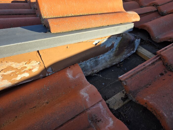 Tak med tegelskivor och en monterad metallplåt under. Vindskivor byts ut och visar övergångsproblem mellan takpannor och plåt.