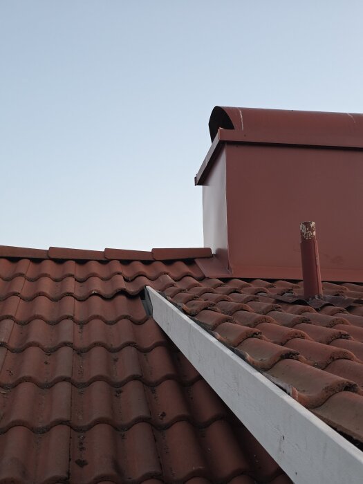 Takkupa med röda tegelpannor, plåt och vit vindskiva. Övergångsdetaljer mellan takpannor och plåt visas.