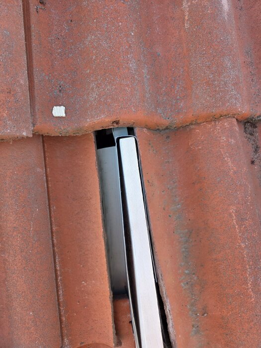 Lucka i tegel och plåt visar problem med övergång mellan vindskiva och takpannor på takkupa.