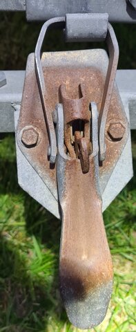 Lås till släp med rostiga delar, används för att hantera tippfunktion, placerat i utsatt läge för stensprut.