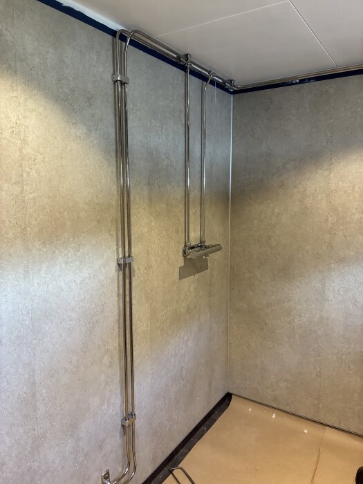 Duschblandare monterad på vägg med Fibo våtrumsskivor och synliga rör, del av pågående renoveringsprojekt.