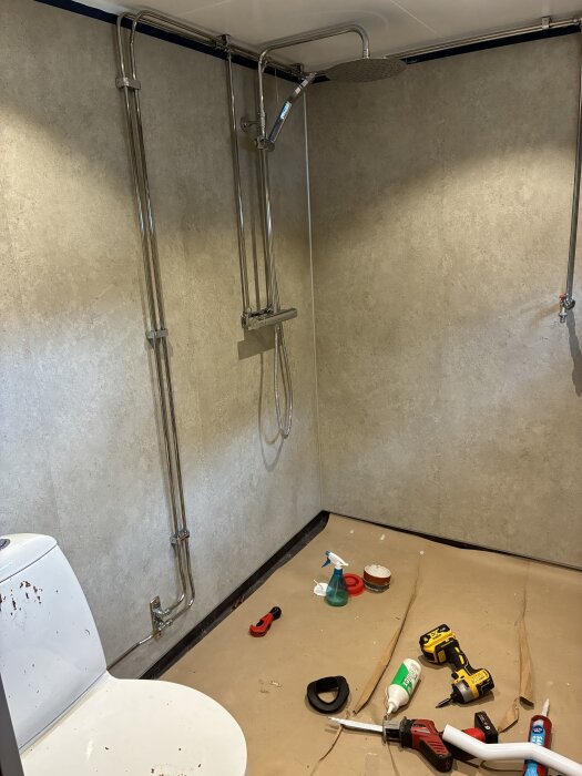 Badrum under renovering med Gustavsberg duschblandare, Ifö toalettstol och verktyg på golvet. Väggar med Fibo våtrumsskivor.