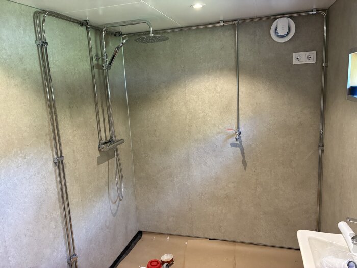 Nyinstallerat badrum med duschblandare från Gustavsberg, väggar med Fibo våtrumsskivor och synliga rörinstallationer, utan duschvägg.