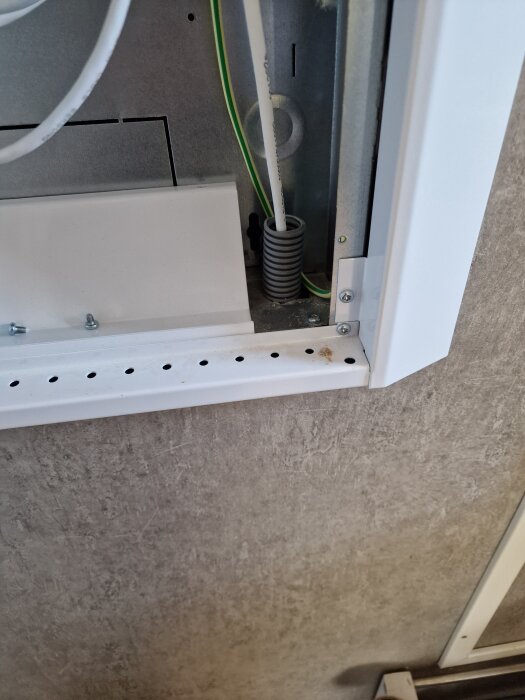 Vit kabel i flexrör från patchpanel genom väggen, del av kablageinstallation.
