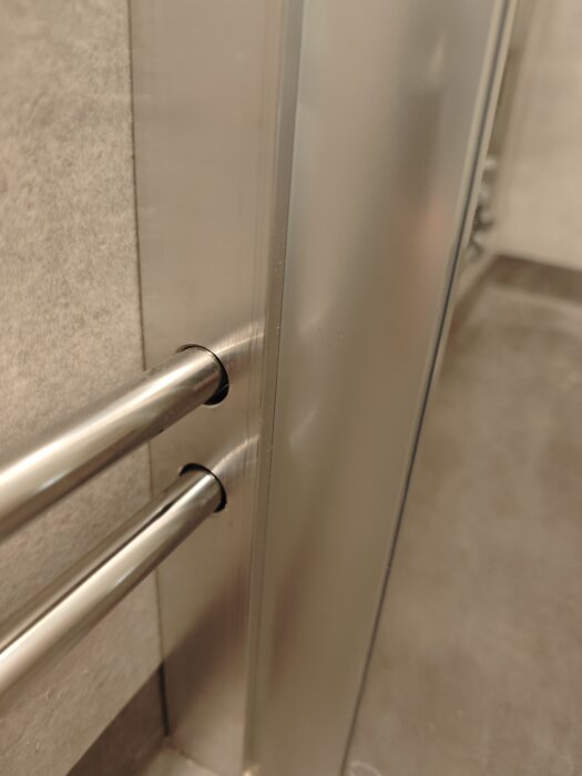 Duschvägg Camargue Vario med egentillverkad rörgenomföringsprofil i metall nära en vägg.