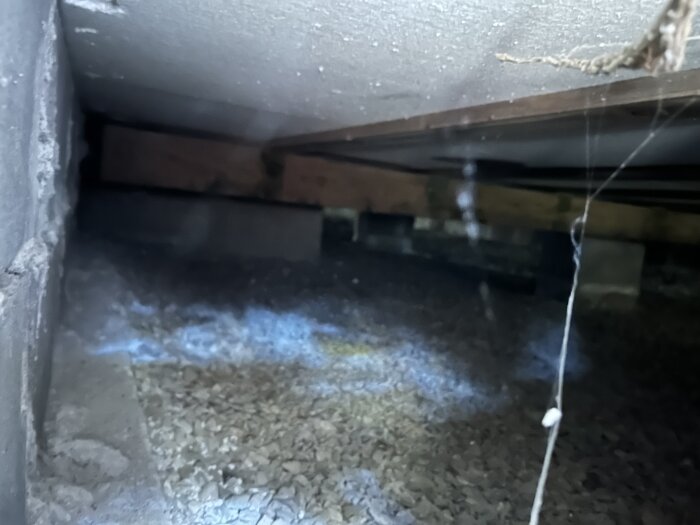 Krypgrund med fuktproblem syns med oisolerade stenar och träbjälkar.