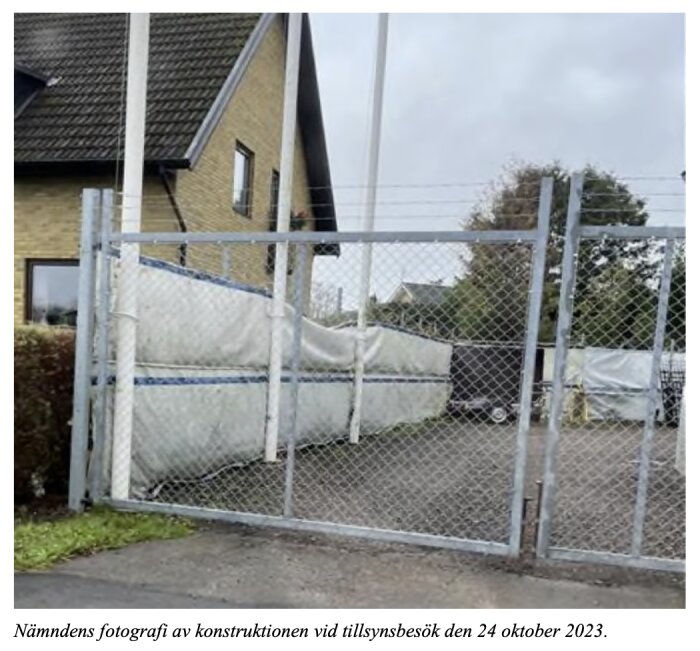 En konstruktion med tygstycke fäst på stängsel vid en byggnad; en del av en domstolsbeslut om bygglovsplikt.