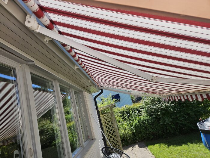 Röd- och vitrandig markis ovanför en uteplats, med tillhörande armatur och bult.