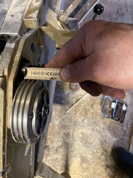 Hand mäter remskiva på Emcostar rikt- och planhyvel med tumstock.